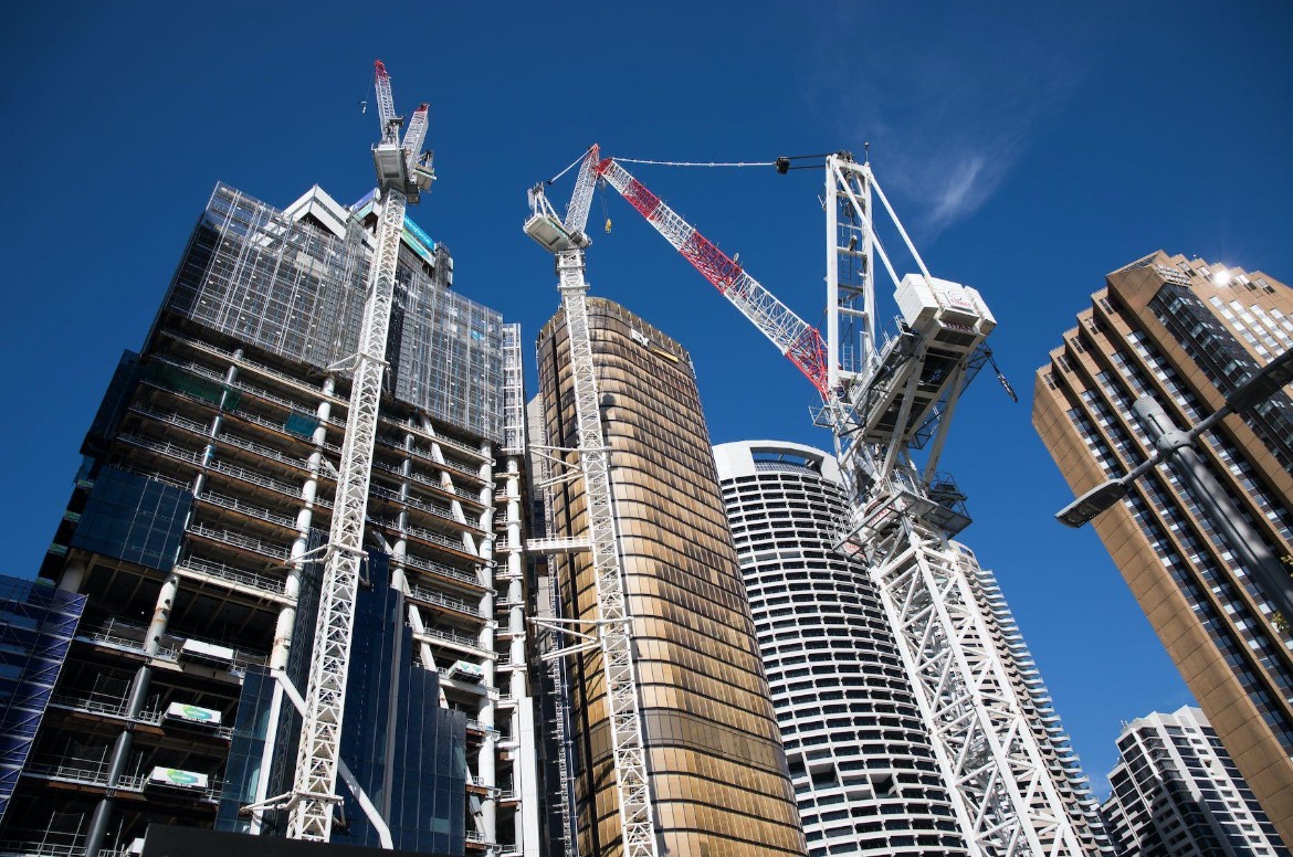 Cranes and skyscrapers under construction against a clear blue sky